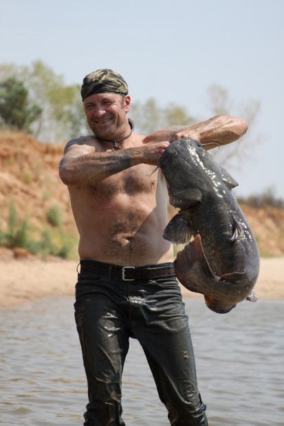 Shane Stillman of Auburn wrangles up a catfish while filming an episode of