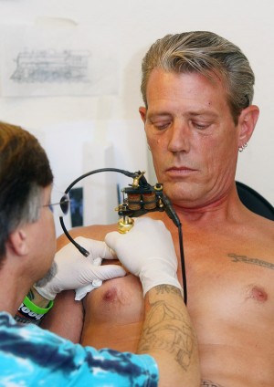 tattoos for men on chest words. Tattoos. Peter Flinn, right, looks on as Tracy Burton tattoos his chest with 