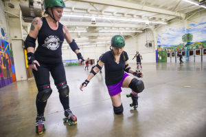 Reporter Skates After Her Derby Girl Dreams : With instruction from “Malice,” left, of the Port City Roller Girls roller derby team, News-Sentinel reporter Sara Jane Pohlman stands without using her hands after falling.
 - Photo by Dan Evans/News-Sentinel