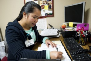Holiday Grind: Locals Share Motives For Working On Christmas: Juvelyn Taylor, activities assistant at Arbor Convalescent Hospital, fills out a participation checklist while working on Christmas Day.
 - Photo by Dan Evans/News-Sentinel