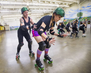 Reporter Skates After Her Derby Girl Dreams : “Malice,” left, of the Port City Roller Girls roller derby team, slowly pushes News-Sentinel reporter Sara Jane Pohlman to teach her proper skating technique at the San Joaquin County Fairgrounds on Thursday, Feb. 7, 2013.
 - Photo by Dan Evans/News-Sentinel