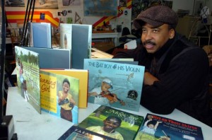 Illustrator E.B. Lewis poses with books he illustrated in his Folsom studio.