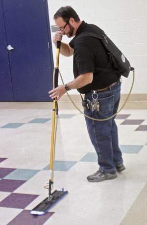 Tony Carnes uses the new green cleaning floor waxing system at Carpenters Middle School