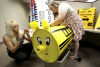 Liza Lopez-Corral, left, the events coordinator with Tucson Association of Realtors, and volunteer Mary Yohem use black tape to decorate the piggy bank. The idea is to make it look like a school bus, complete with wheels. | A.E. Araiza / Arizona Daily Star