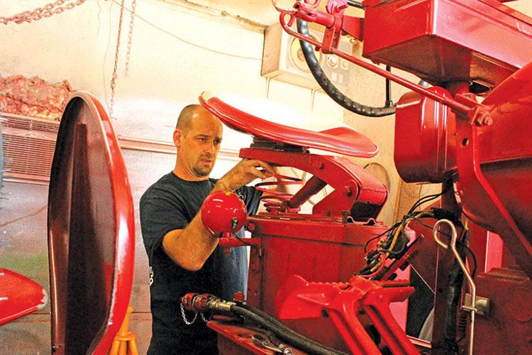 Eric Shuster removes a tractor seat
