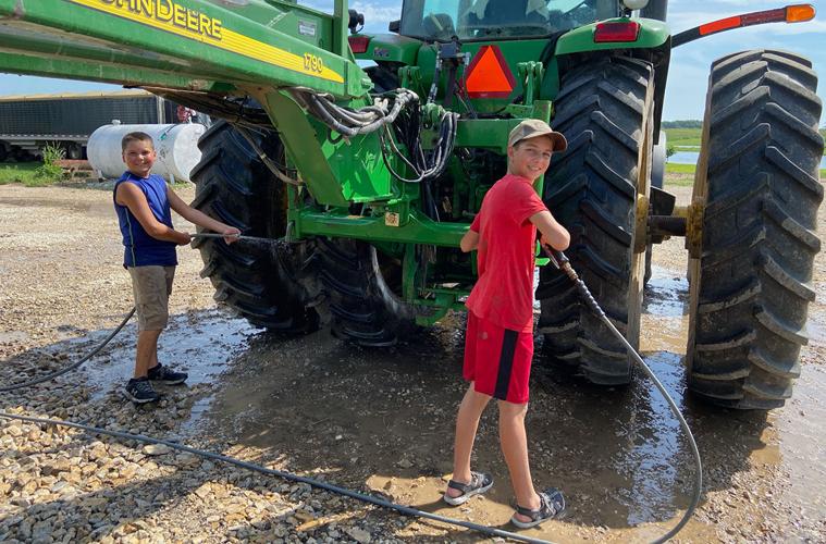 Levi and Nathan Wright help clean a tractor on their family farm.