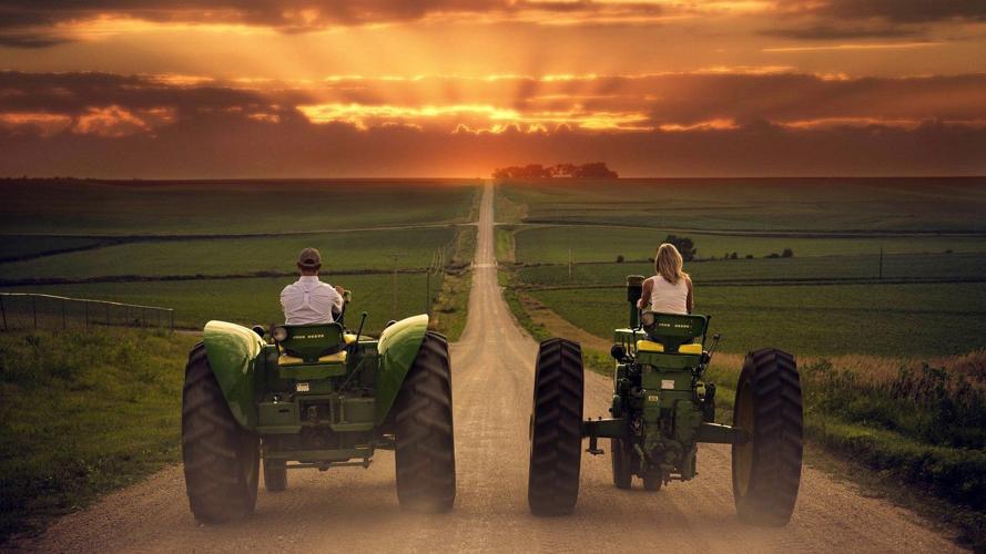 Farm couple riding down road on tractors