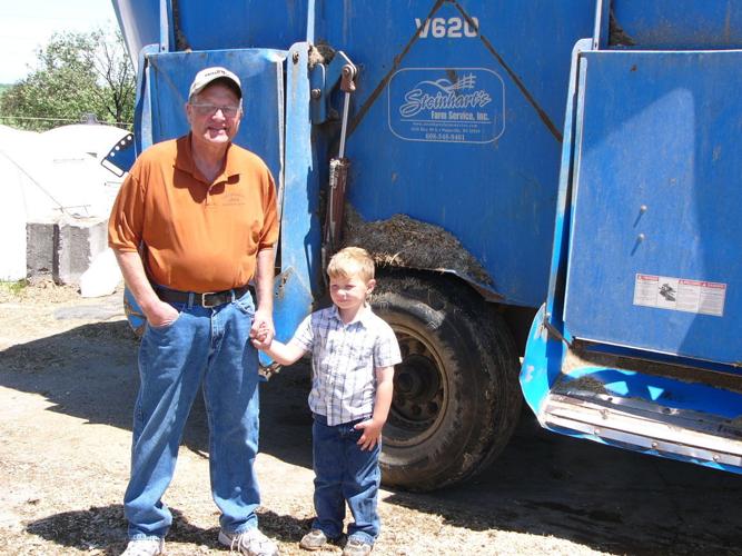 Clay Bernick and grandson by feed mixer