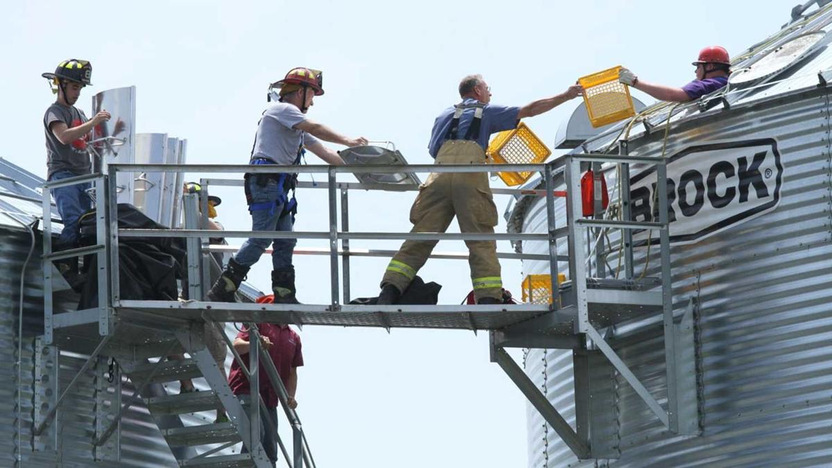 Firefighters pass equipment to a grain bin