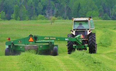 Tractor in field cuts hay