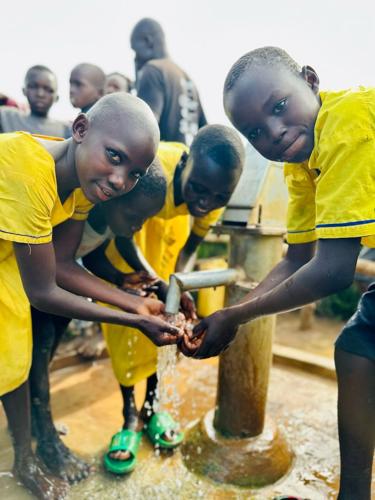 Children enjoy clean water at a newly drilled well dedication.jpg
