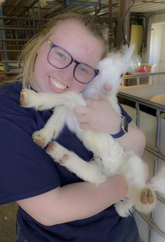 Sophie Koehler holds a kid, a baby goat, after bottle-feeding it.