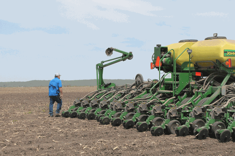 farmer walking by planter in field