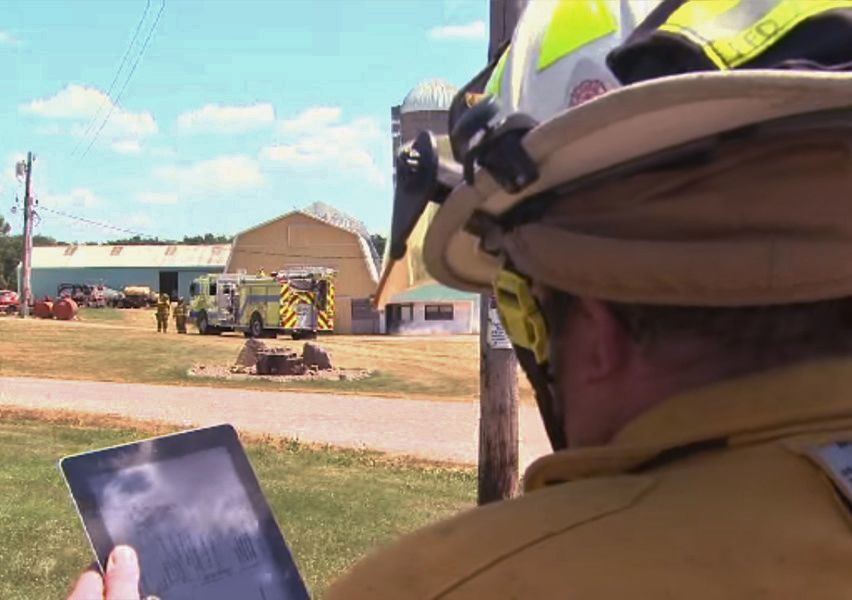 Firefighter looking at computer pad at farm