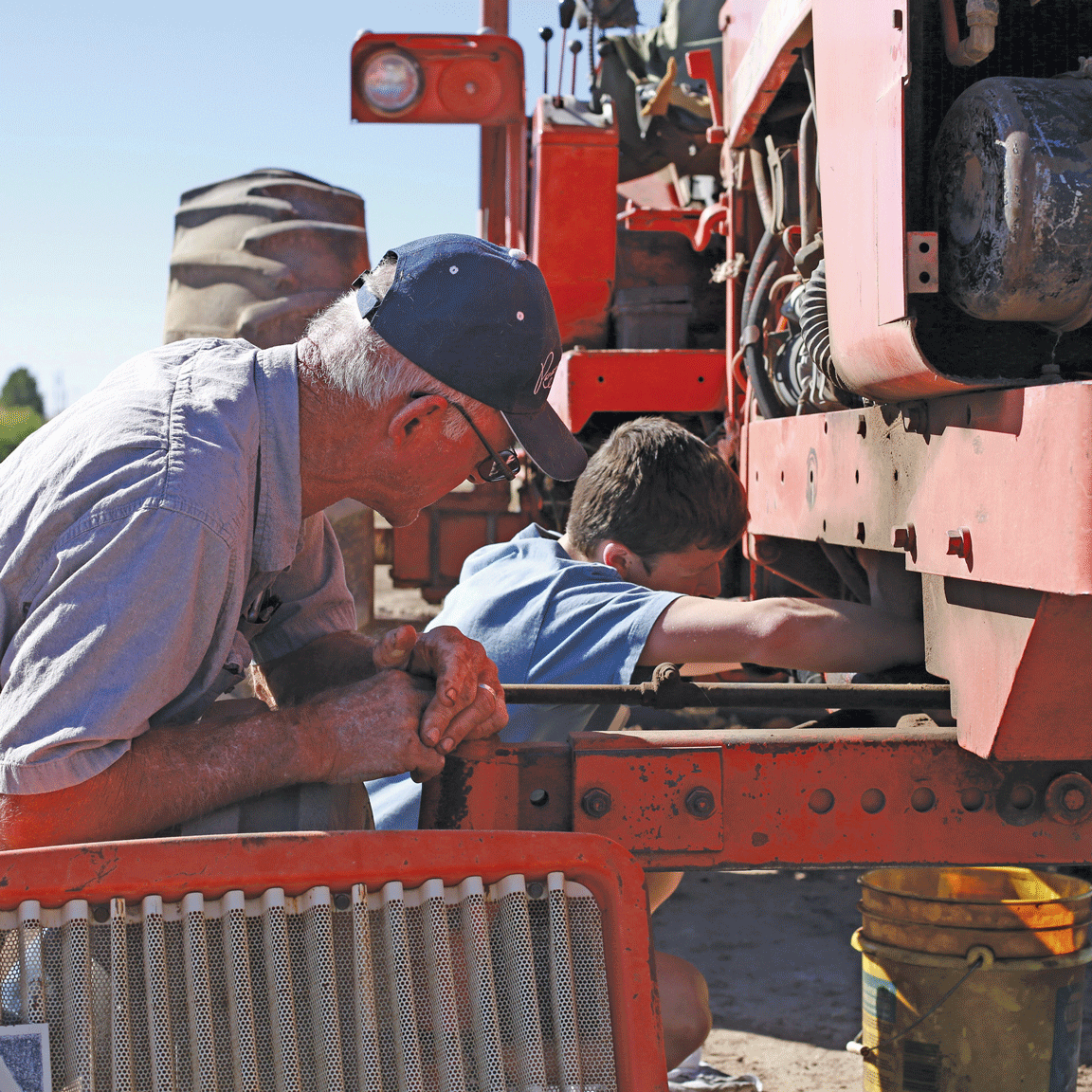 kid and farmer working on tractor