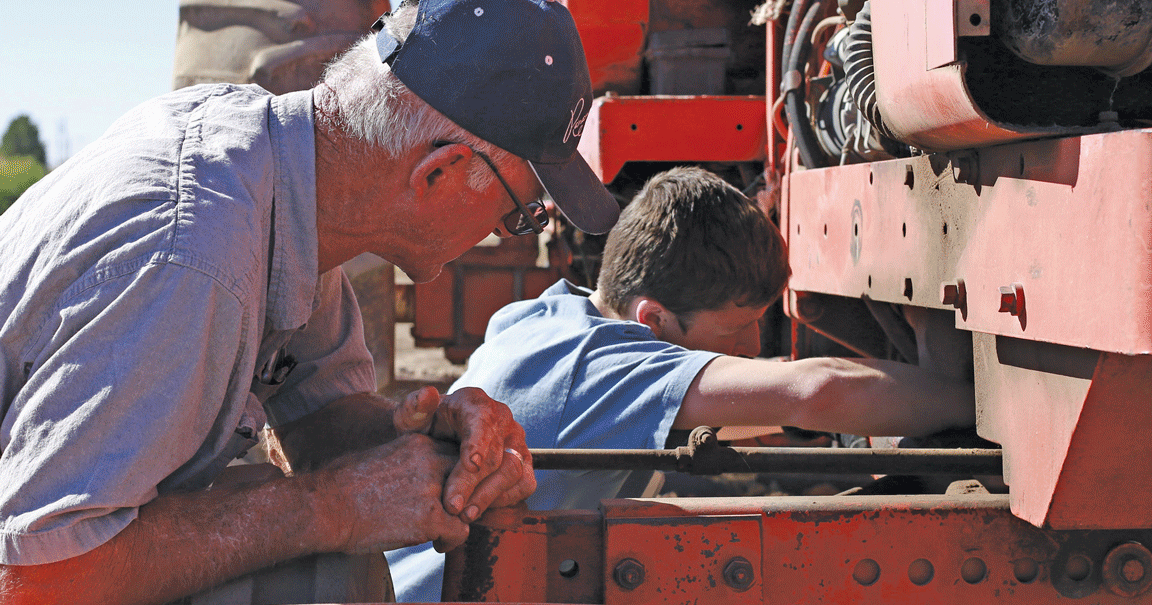 kid and farmer working on tractor