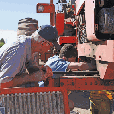 kid and farmer working on tractor