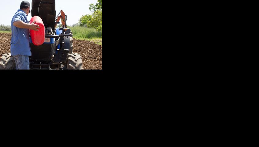 Farmer puts diesel fuel to the tractor
