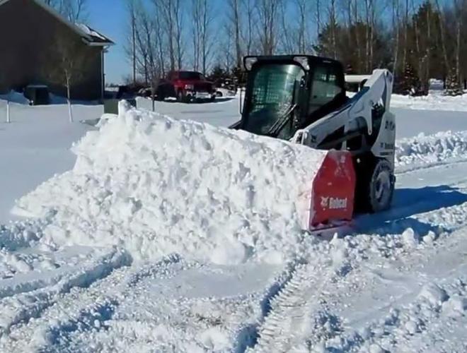 Skid steer plowing snow