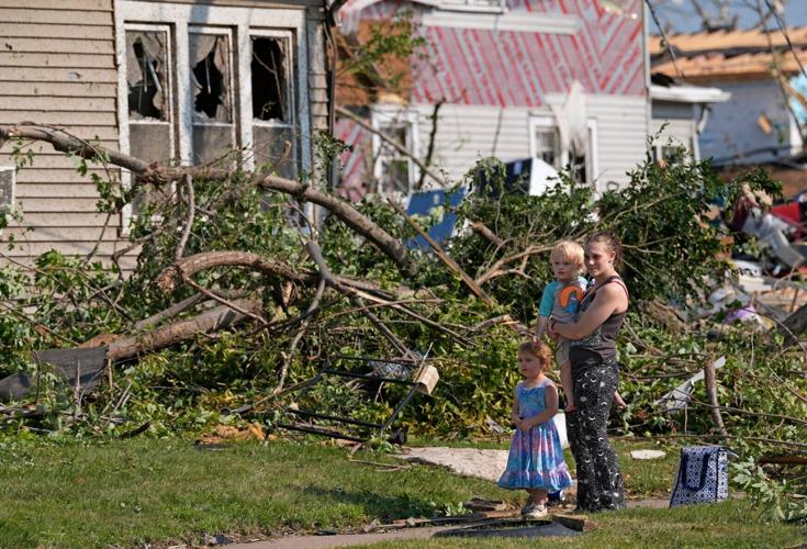 The Dins family stay together in front of their father’s home following severe weather, including a tornado Monday, July 27,