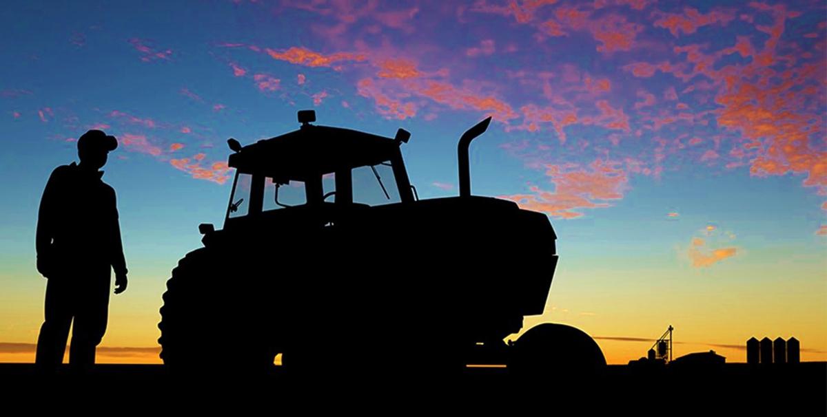 Farmer and tractor in field at sunset