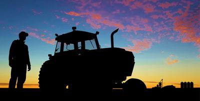 Farmer and tractor in field at sunset
