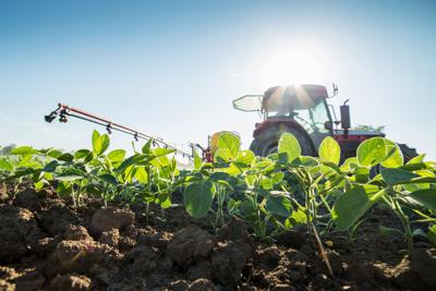 Tractor spraying soybean crops with pesticides and herbicides