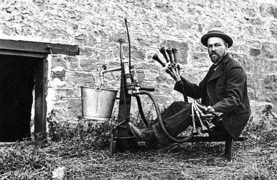Man poses with milking machine.