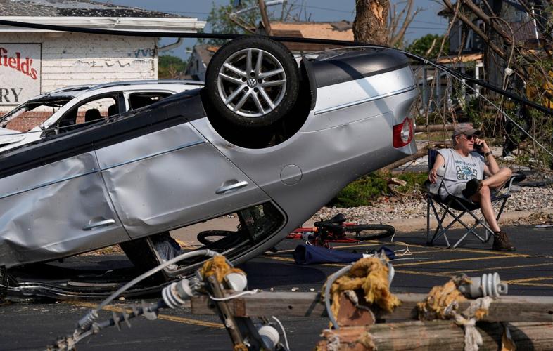 John Dobish sits next to his destroyed car in the parking lot of Manderfield’s Home Bakery following severe weather, including a