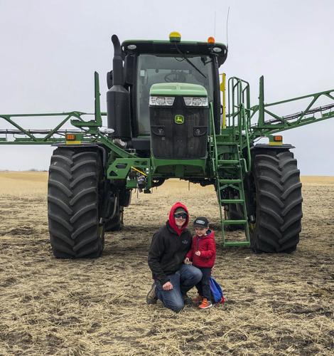 Jake Leguee poses on his farm with his son Grayson, 4