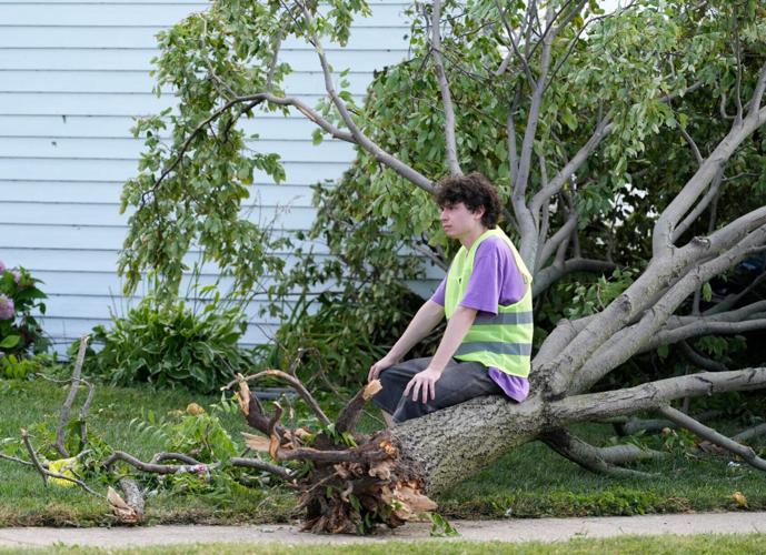 Nico Padilla Hernandez takes a moment to rest while trying to remove a fallen tree from his car following severe weather,