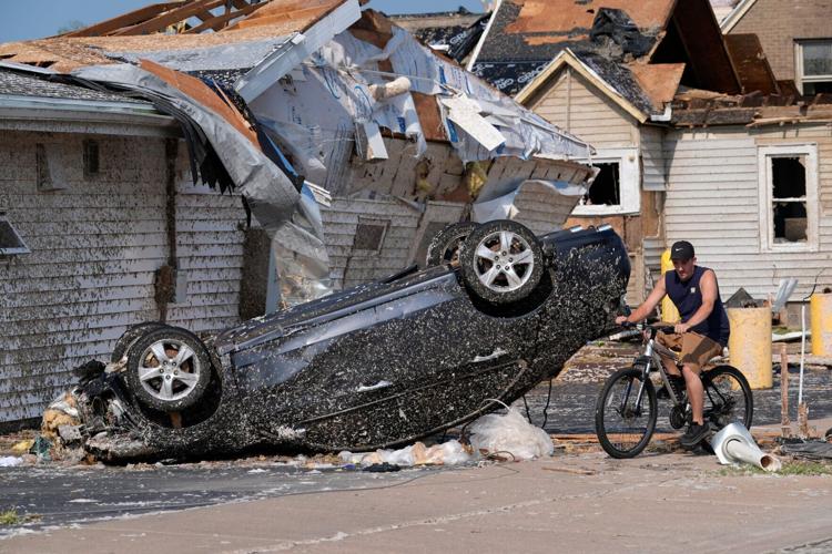 A bicyclist passes an overturned car following severe weather, including a tornado Monday, July 27, 2026, in Menasha, Wisconsin.