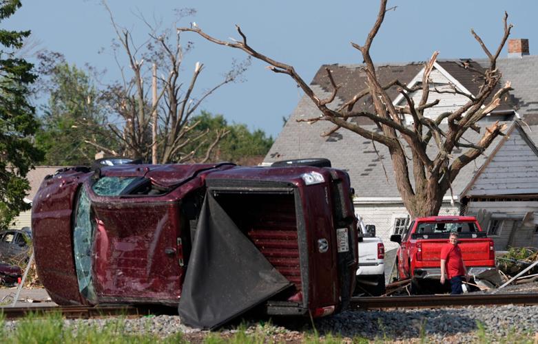 A man walks past an overturned vehicle following severe weather, including a tornado Monday, July 27, 2026, in Menasha,