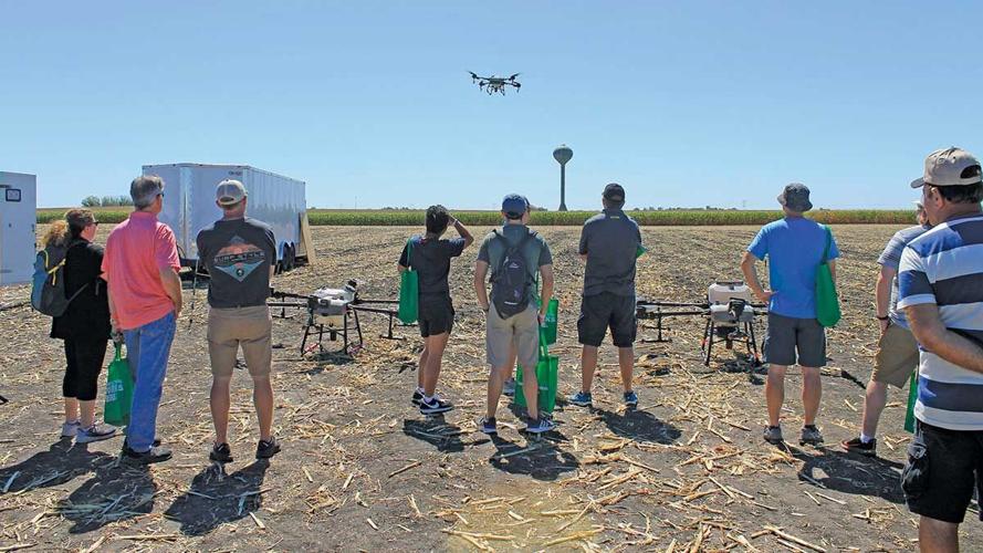 attendees watch a drone on a spraying demonstration