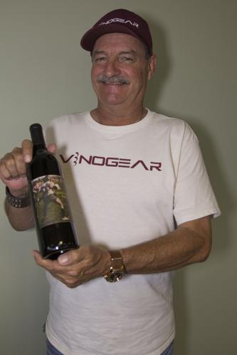 Jeff Wallace holds a bottle of his Rugby Red. He made the wine and the label has a photo of him as a young rugby player.