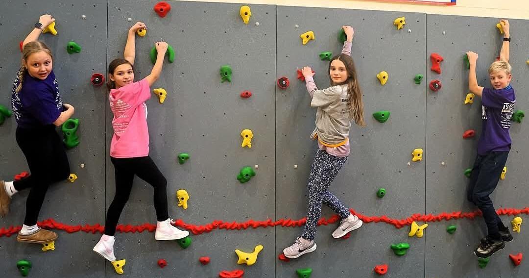 Students celebrate the climb after funds raised for rock wall go sky