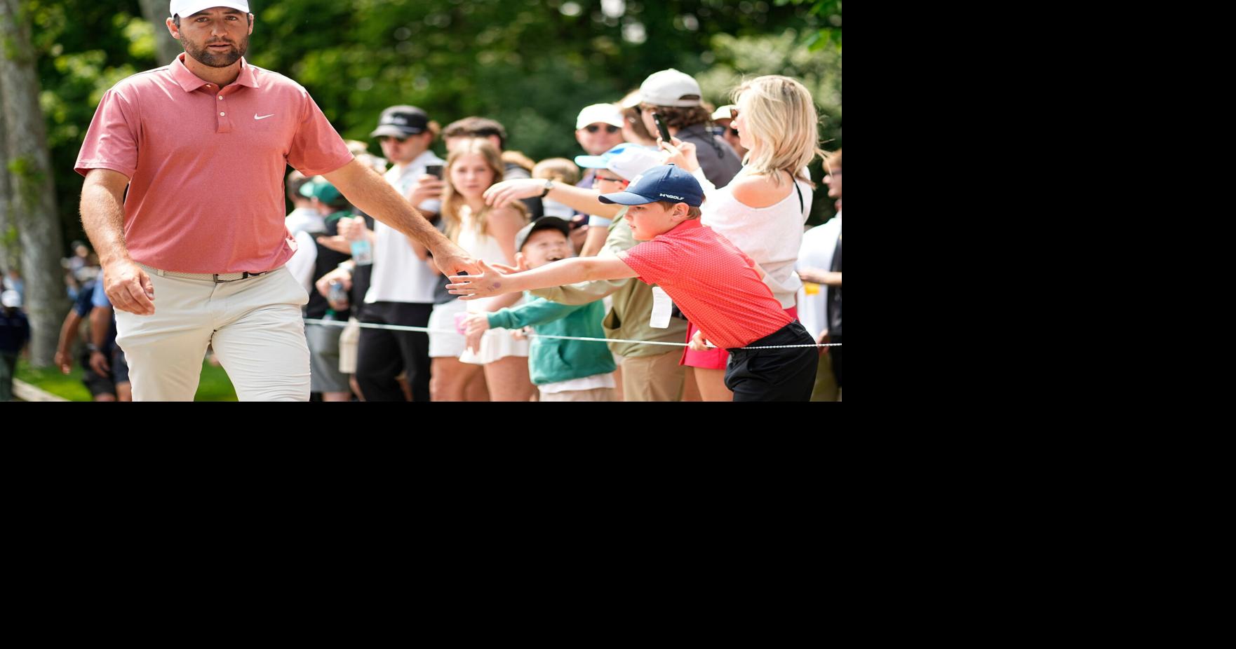 Scottie Scheffler shares a moment with a young fan as he walks to the third tee during the third round of the 2025 Memorial