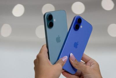 FILE PHOTO: An attendee holds two iPhones 16 as Apple holds an event at the Steve Jobs Theater on its campus in Cupertino