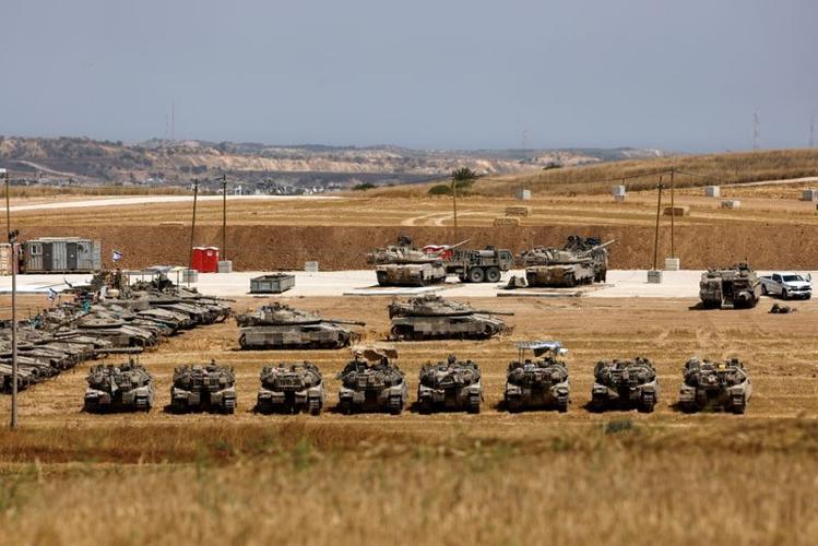 Israeli tanks and APCs stand near the border between Israel and the Gaza strip, as seen from the Israeli side of the border