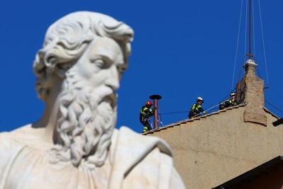 Firefighters work to set a chimney on the roof of the Sistine Chapel, ahead of the conclave, at the Vatican