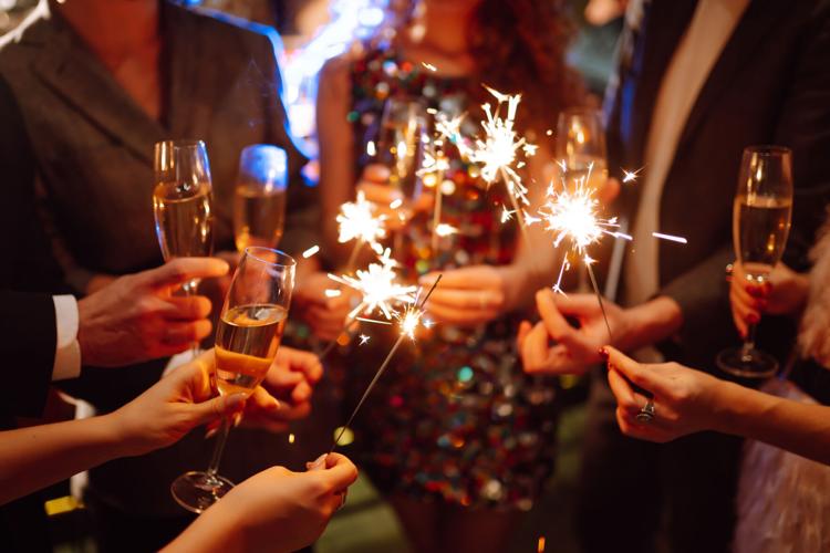 Glowing sparkles in hands. Group of happy people enjoying party