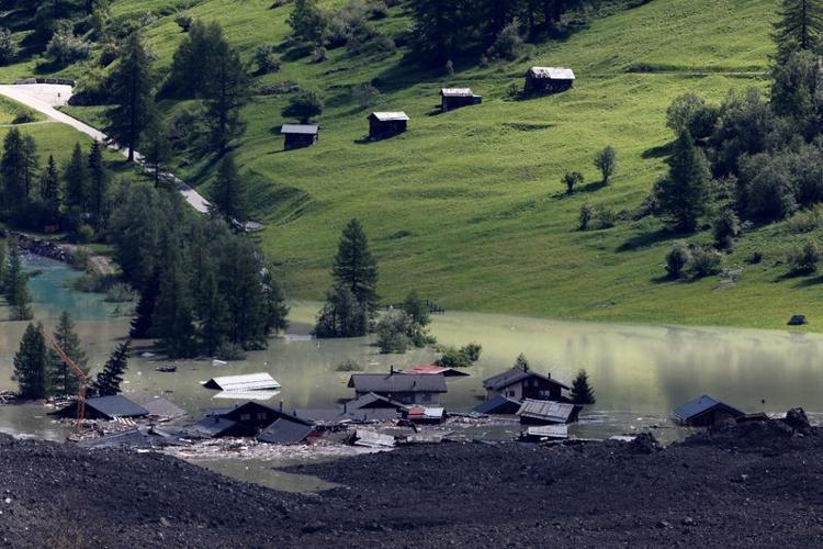 A few remaining houses are seen after a massive rock and ice slide covered most of the village of Blatten