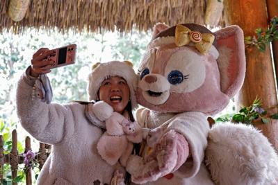 A fan takes a selfie with a performer dressed as the character LinaBell at Shanghai Disneyland
