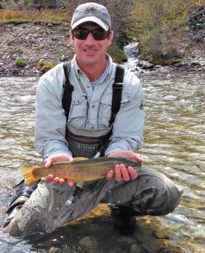 Matt Scott is playing a large trout on his fly rod. South Fork of