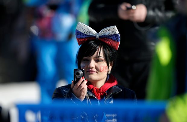 A woman wears a bow in the colors of the Russian flag