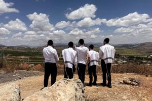 A group of ultra-Orthodox Jewish men looks towards southern Lebanon, from the Israeli side of the Israel-Lebanon border, in northern Israel