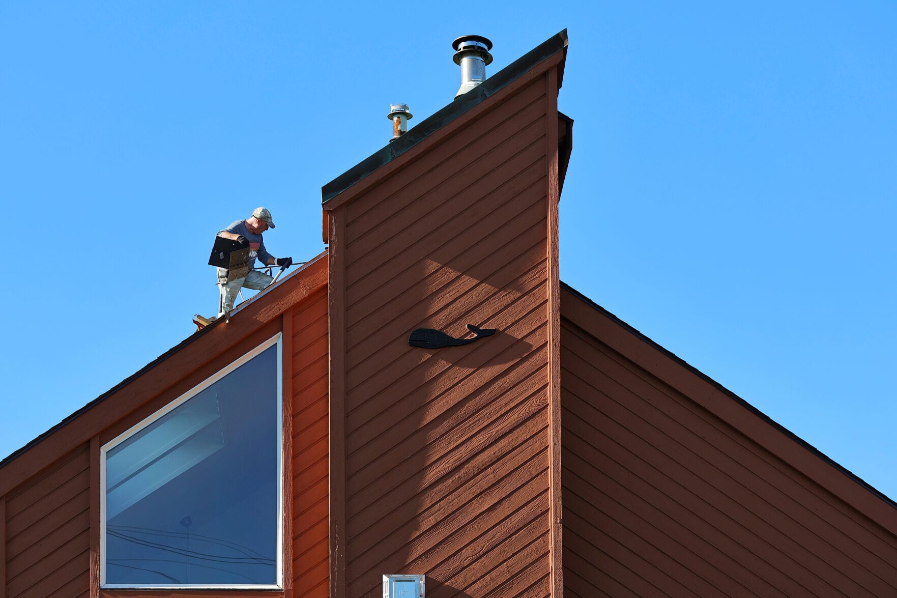 On October 7, 2026, a roofer removes shingles from a house in New ...