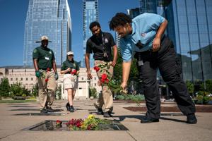 John Cleveland, right, of Nashville, stops to place flowers on Dolly Parton’s plaque at Walk of Fame Park in Nashville, Tenn.,