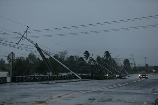 Vehicles speed past damaged electric posts along a highway in Albay province, south of Manila Fung-wong made landfall