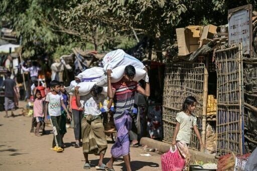 Rohingya youths carry sacks of relief aid at the Kutupalong refugee camp in Ukhia on December 20, 2025